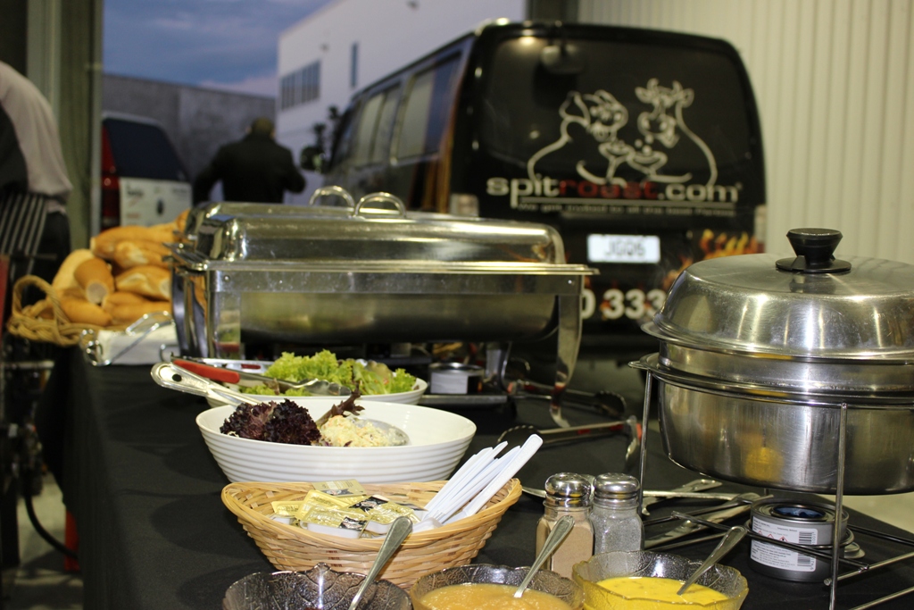 Buffet food set out on a table in a warehouse with Spitroast.com van in the background